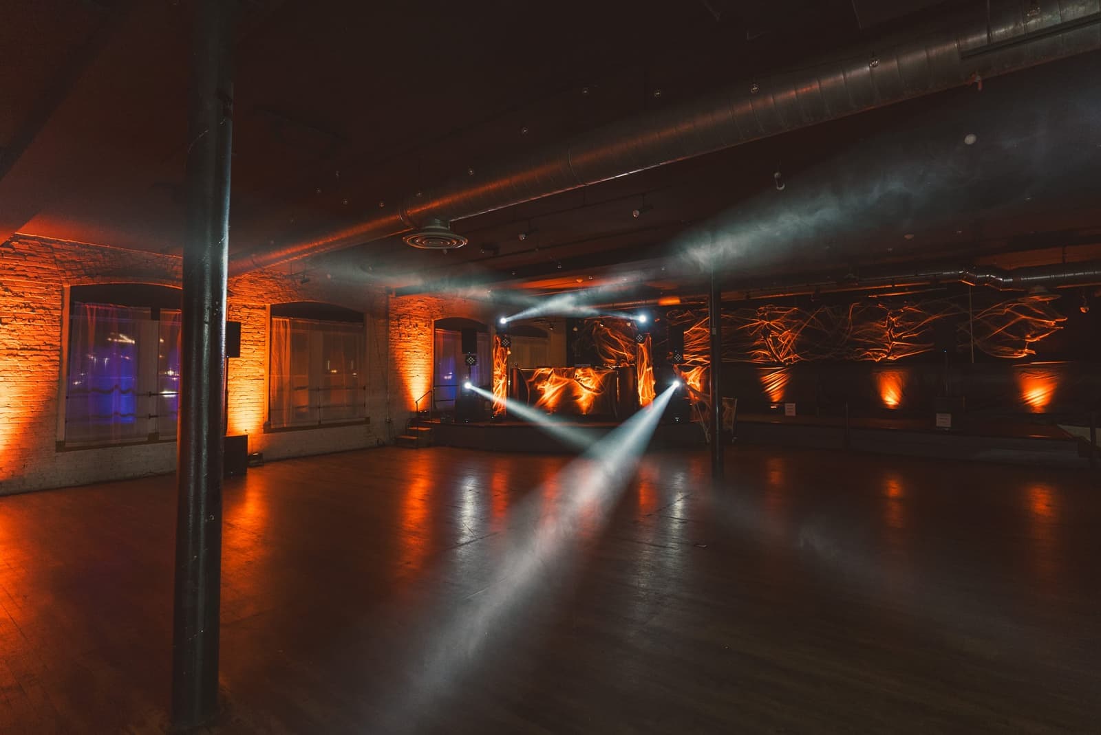 Empty venue floor lit by moving lights during Amped production setup