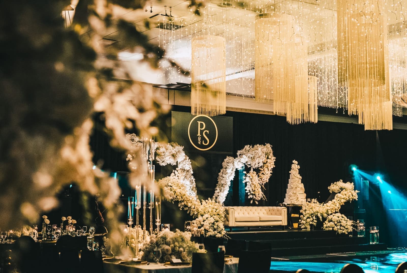 Elegant reception stage framed by hanging string-light chandeliers and white florals