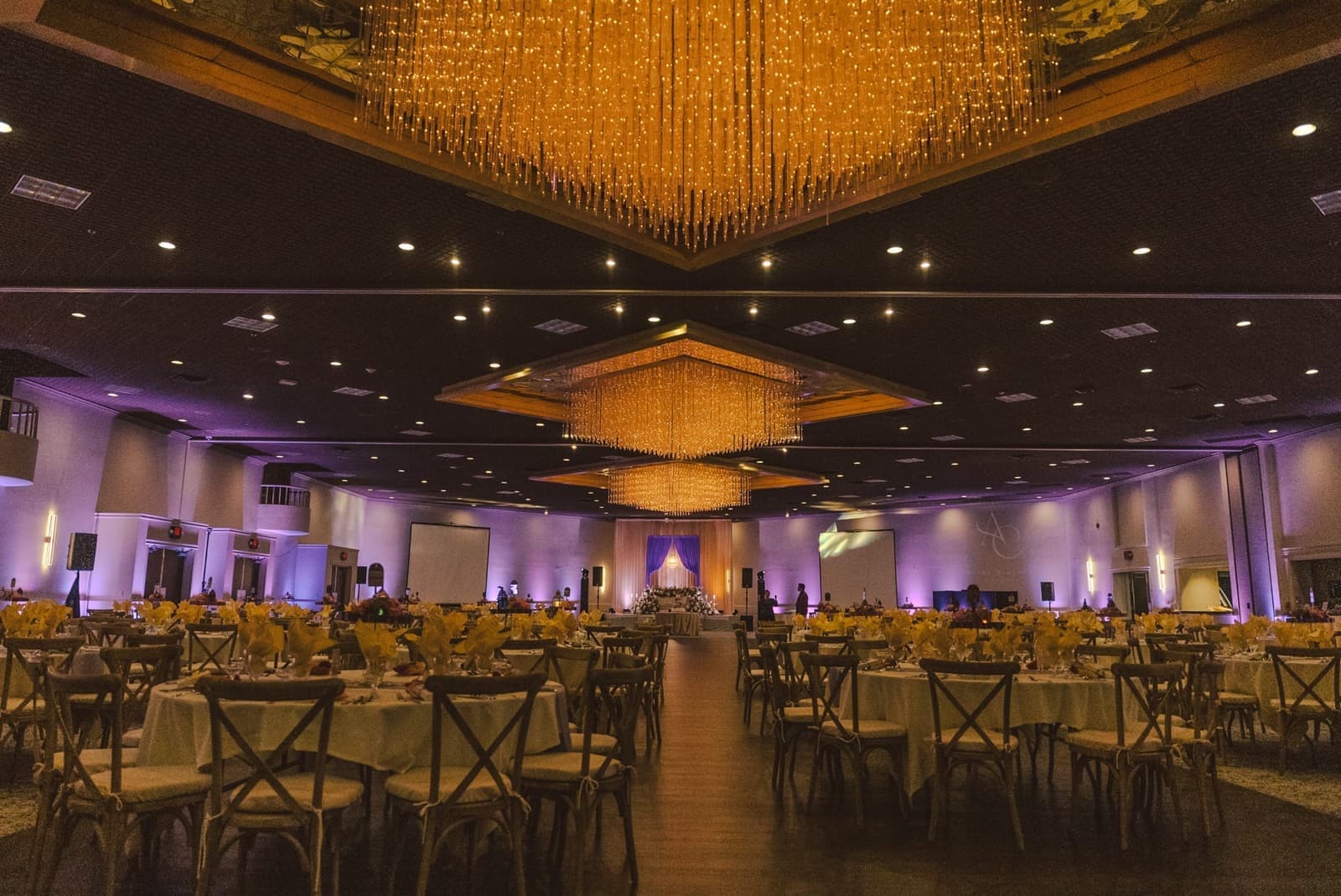 Elegant wedding ballroom lit with hanging string-light chandeliers and purple uplighting