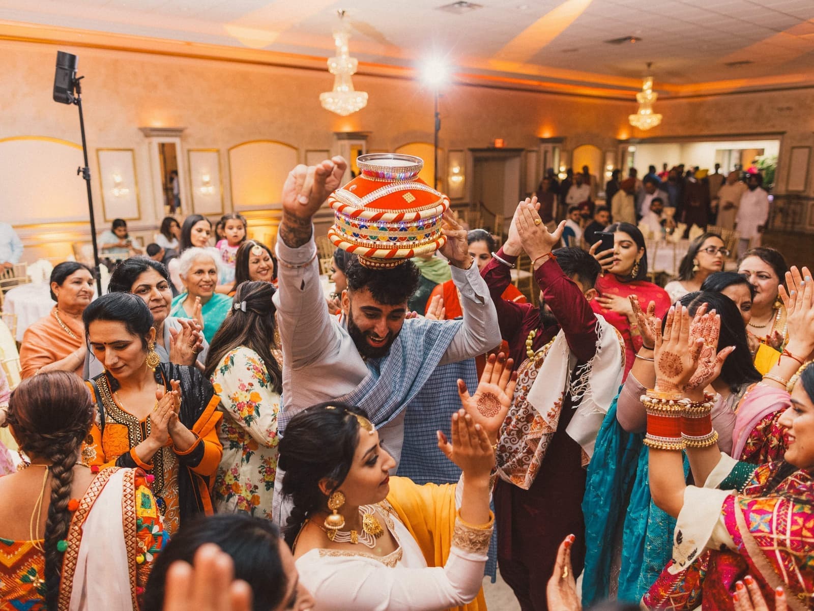 Guests dancing during a Jaggo with a decorated pot balanced overhead